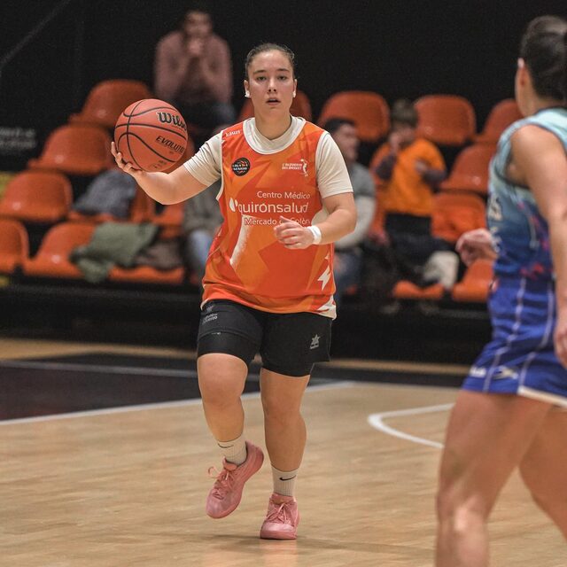 Jugadora de baloncesto botando con la camiseta naranja de su club
